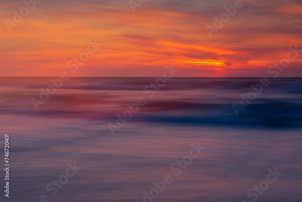 Fototapeta blurred sea, illuminated with the colors of the setting sun