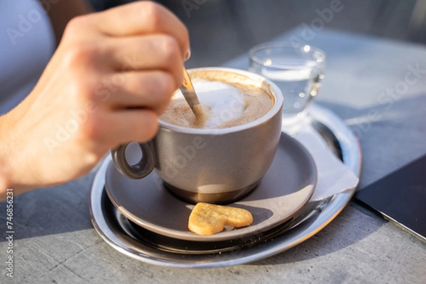 Obraz cup of cappuccino coffee with a female hand