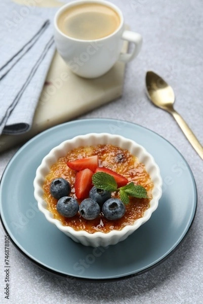 Fototapeta Delicious creme brulee with berries and mint in bowl served on grey textured table