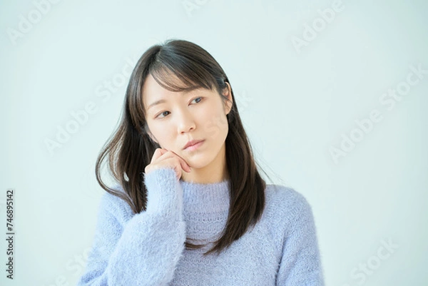 Fototapeta あごに手を当てて、考え事をしている若い女性