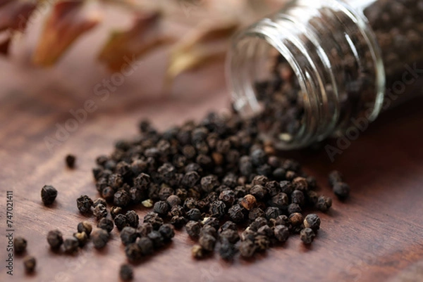 Fototapeta 透明容器からこぼれ落ちる黒胡椒の実