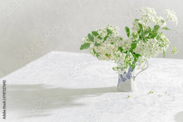 Fototapeta Beautiful spring white flowers in the rastic vase on the table. Whaite tablecloth and whate bouquet