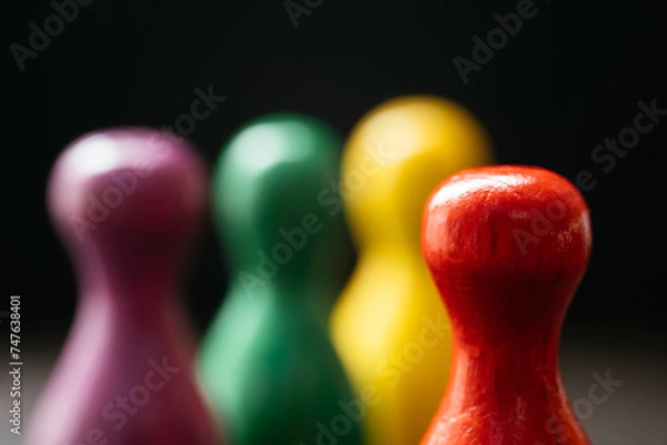 Fototapeta Three pawn-style playing pieces standing together and a red one in a distance from them