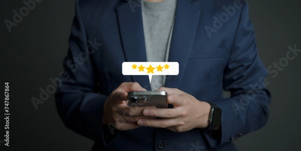 Fototapeta close up Man hand using smartphone with popup five star icon for feedback review satisfaction service, Customer service experience and business satisfaction survey.
