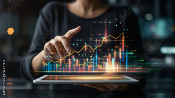 Fototapeta Businessman holding tablet and showing a growing virtual hologram of statistics, graph and chart with arrow up on dark background. Stock market. Business growth, planing and strategy concept.
