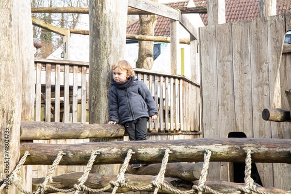 Fototapeta Child on the playground, climbing into the net.