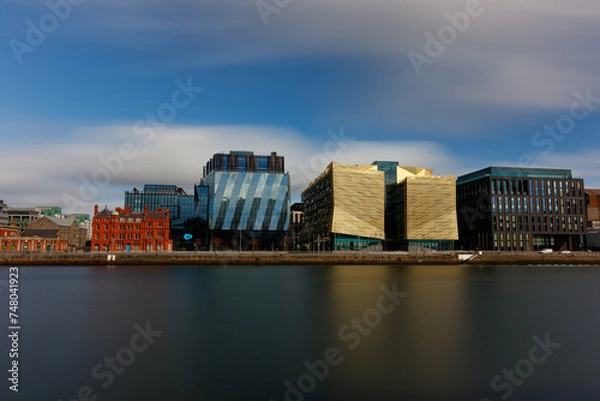 Fototapeta Dublin, Ireland, Dockland, modern building business center cityscape by Liffey river view during sunny day in background. europe