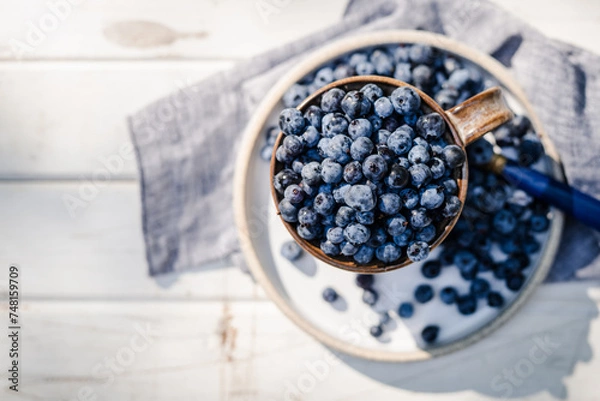 Obraz A Plate of Fresh Blueberries on a Sunlit Table.