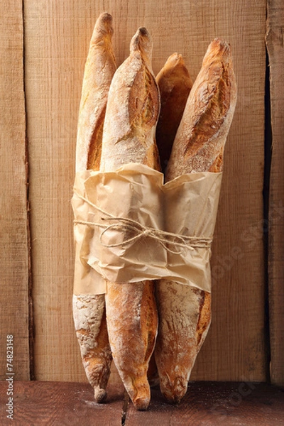 Fototapeta French baguettes in paper on wooden background