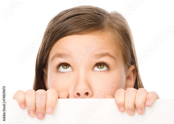 Fototapeta Little girl is looking from out blank board