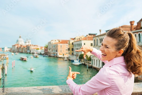 Fototapeta Girl framing with hands while standing on bridge in venice