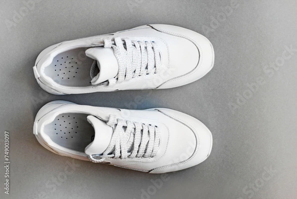 Obraz White leather sneakers on a gray background.