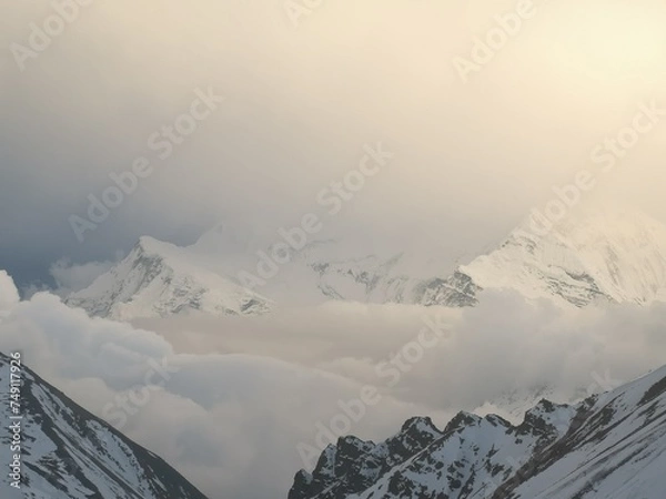 Fototapeta Majestic peaks obscured by billowing clouds, their tops adorned with a pristine layer of glistening snow.