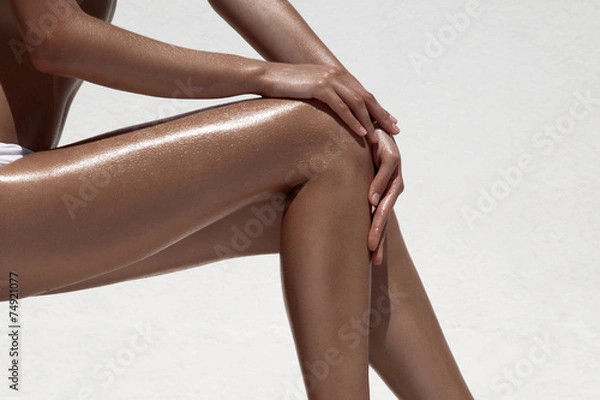 Fototapeta Beautiful woman tan legs. Against white wall.