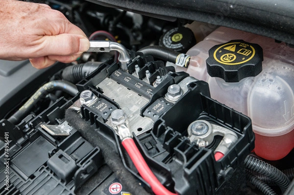 Fototapeta Mani che riparano un motore di automobile con una chiave