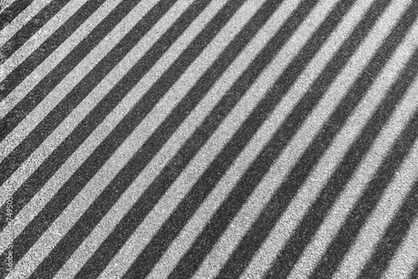 Fototapeta Striped shadow on gray asphalt. Shadow from iron railings on the sidewalk