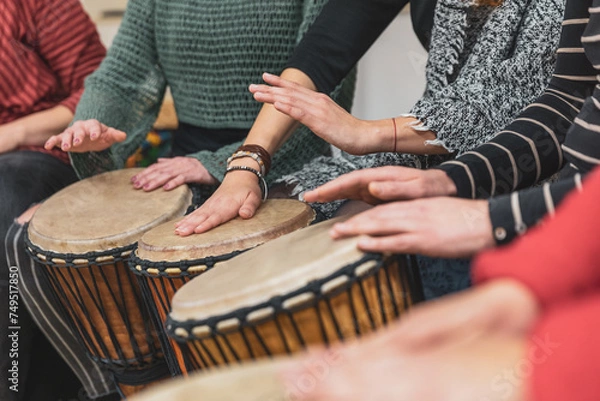 Fototapeta Group of people playing drums during a music therapy lessons, jembe drum, drumming concept