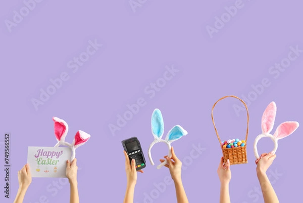 Fototapeta Women with payment terminal, bunny ears and Easter eggs on lilac background. Online shopping