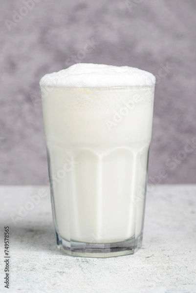 Fototapeta Sparkling buttermilk. Close-up. A glass of ayran on a gray background