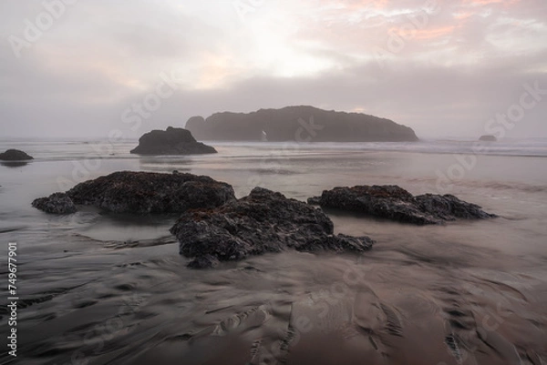 Fototapeta A rocky shoreline with a foggy sky in the background