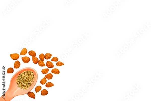 Fototapeta Plastic spoon with spices and apricot kernels for cooking,drinks,baking on white