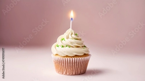 Fototapeta Lit candle decorating a cupcake amidst soft pink setting 