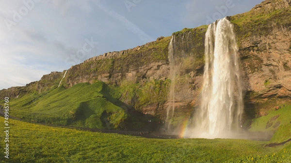 Fototapeta The Seljalandsfoss waterfall on the south coast of Iceland bathed in the otherworldly light of the midnight sun. The waterfall drops 60 meters and is part of the Seljalands River.
