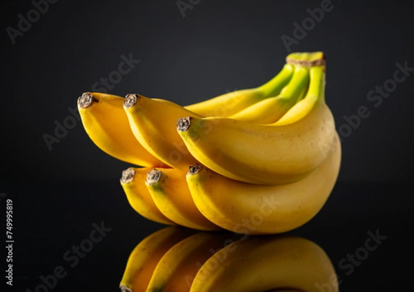 Obraz Bananas on a black reflective background.