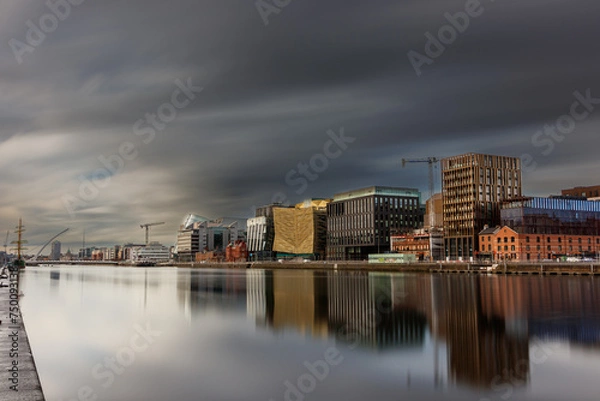 Fototapeta Dublin, Ireland, Dockland, modern building business center cityscape by Liffey river view during sunny day with tall ship and Samuel Beckett bridge in background. europe