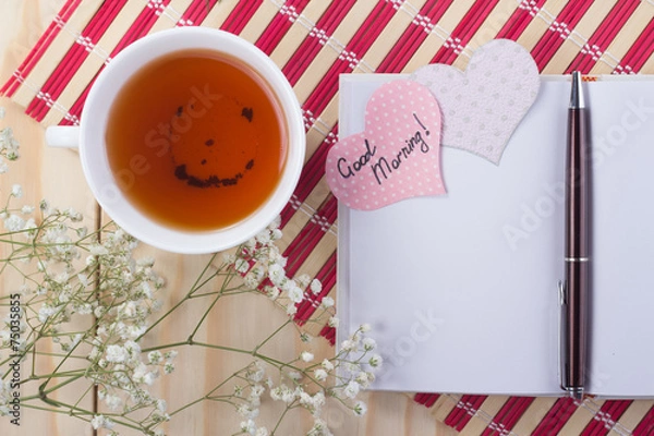 Fototapeta open notebook with a cup of tea on striped napkin