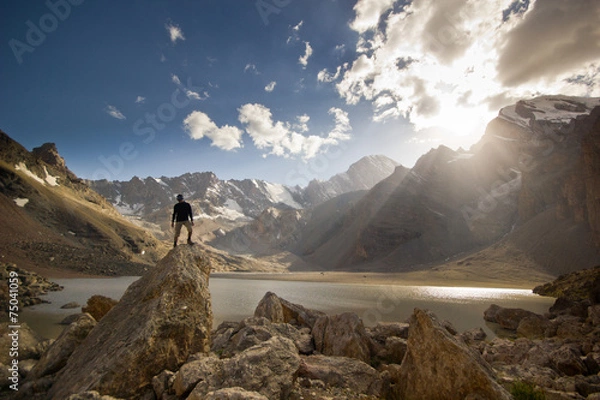 Obraz man on a cliff at sunset near the mountain lake