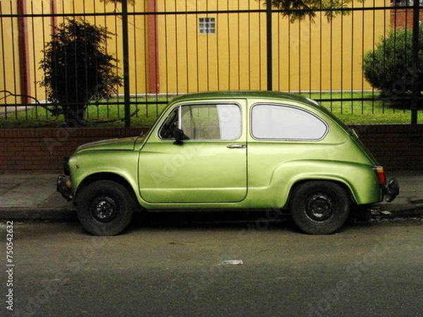 Fototapeta An abandoned green Fiat parked in front of a building in Buenos Aires, Argentina