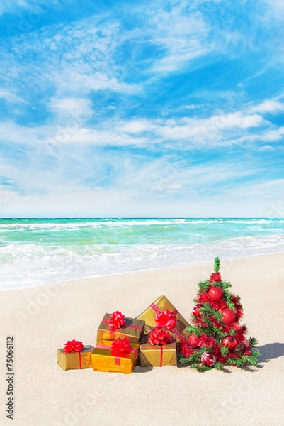 Obraz Christmas tree and gift boxes on sandy beach