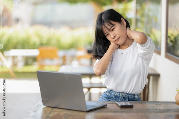 Fototapeta Asian women experience neck pain while working with a laptop, being stressed, or using a computer for a long time.