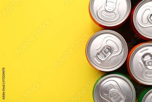 Fototapeta Energy drink in cans on yellow background, top view. Space for text