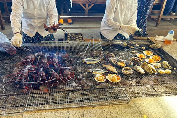 Obraz 海女小屋で新鮮な伊勢海老や貝、魚を炭火焼きにする海女さん 三重県日本
