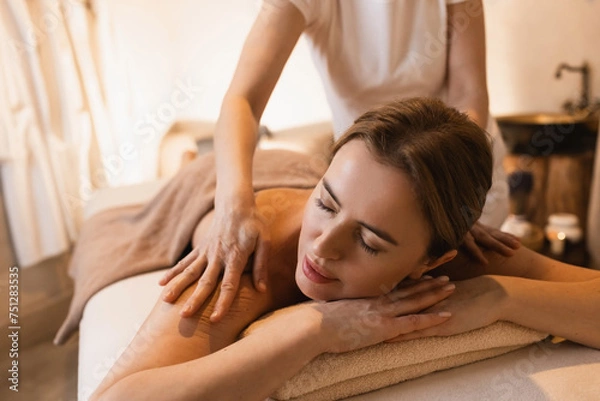 Fototapeta Happy woman enjoying back massage while time weekend on spa resort. Beautiful woman relaxes while back massage