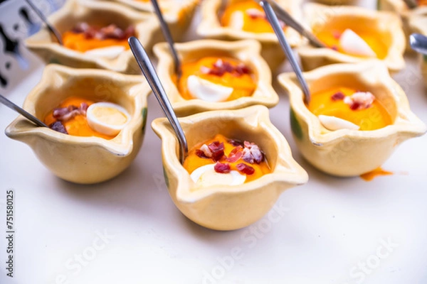 Fototapeta Several glasses of salmorejo, with ham, egg, olive oil, typical Andalusian, at an event in a restaurant,