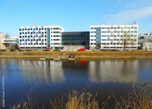 Fototapeta River in early spring. City landscape in Riga, Latvia, Europe. View of the educational buildings of the State Riga Technical University.