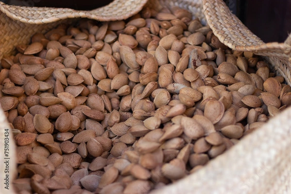 Obraz Close-up of delicious raw Marcona almonds in shell in an esparto grass basket.