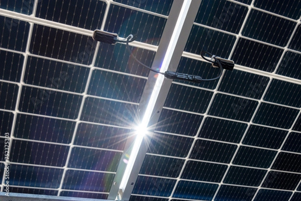Fototapeta Bilateral solar panels, photovoltaics? with natural sun flare - alternative source of electricity, concept of sustainable and renewable resources. Panoramic backwards view.