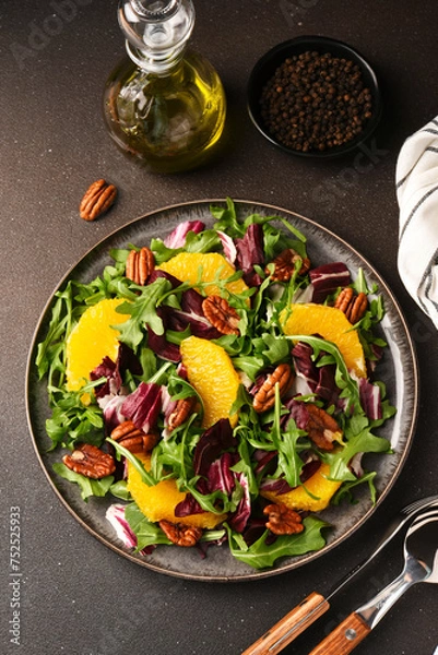Fototapeta Arugula, orange and pecan salad. Radicchio salad on brown background