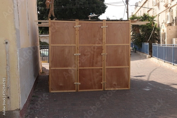 Fototapeta Sukkah for Sukkot from wooden sides and sheets on the street