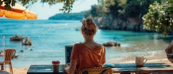 Obraz Digital nomad working on laptop at beach cafe, serene sea view in background, epitome of freedom.