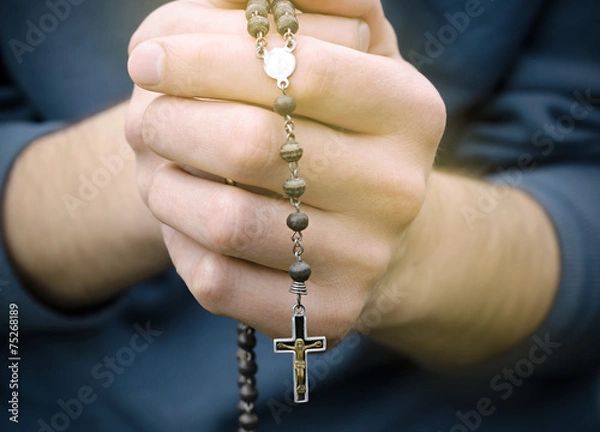 Obraz man prays with a rosary in hands