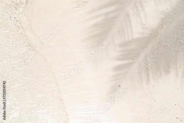 Fototapeta Palm leaf shadow on sand beach background with sun glitter on water surface