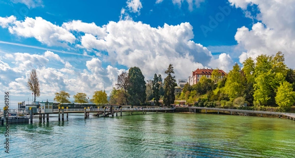 Fototapeta Large panorama of the pier on the east side of Mainau Island, the famous island in Lake Constance (Bodensee). Visitors are walking on the landing stage towards the entrance of the tourist attraction.