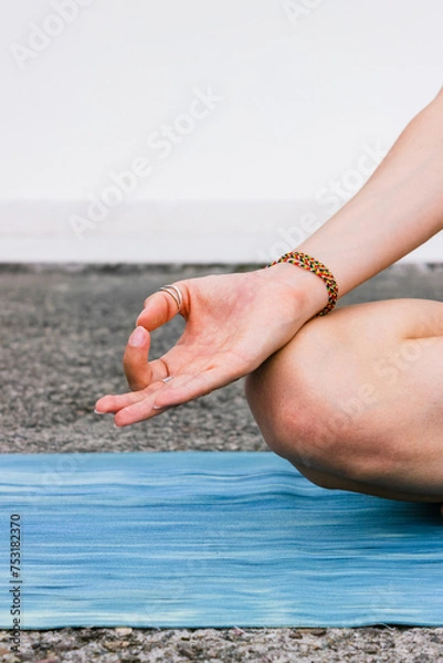 Fototapeta Lotus pose with mudra gesture. Woman practicing yoga on yoga mat, breathing and meditating. Wellbeing and mindfulness concept.