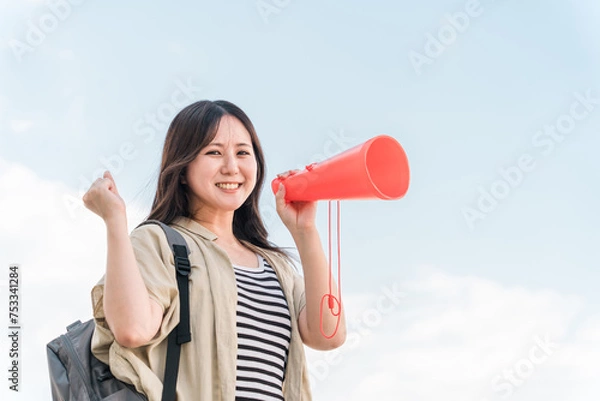 Fototapeta 青空の下でメガホンで応援・声援・エールを送る若いアジア人女性
