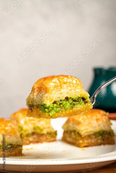 Fototapeta Pistachio baklava. Turkish and Arabic cuisine delicacies. He is holding a slice of baklava with a fork. Close up